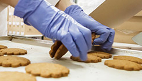 Gloved hands picking up biscuits