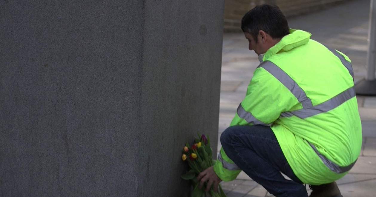 A protester placing flowers at the 'Unknown construction worker' statue in London