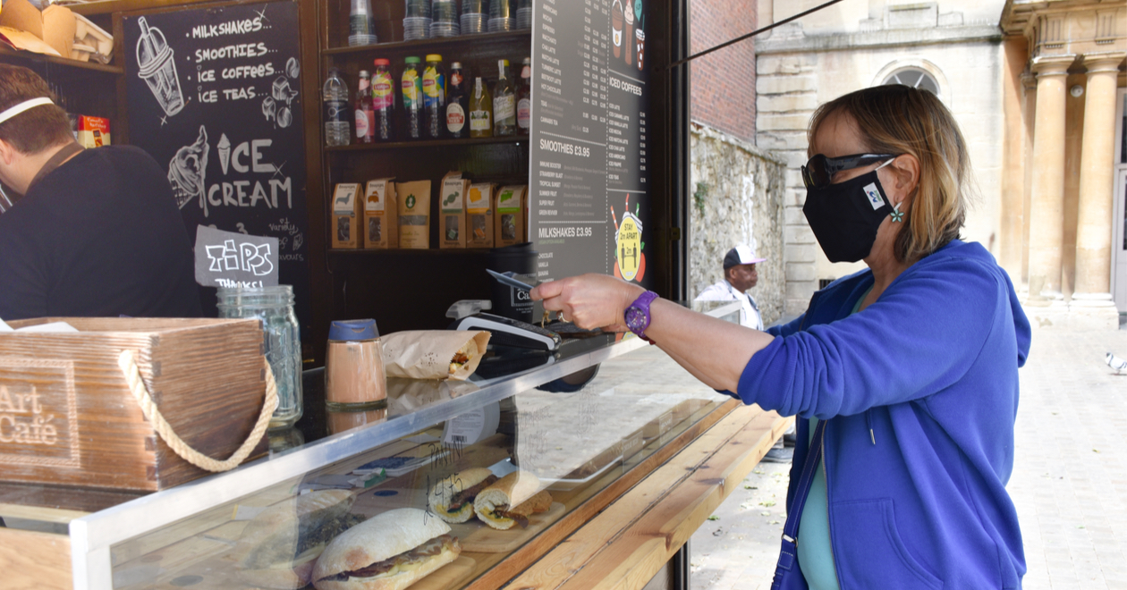 A woman pays with her phone at an outdoor coffee shop