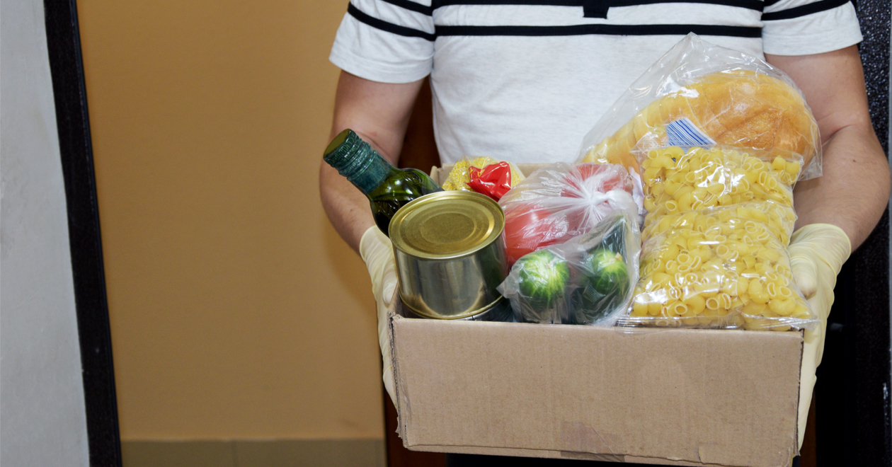 A food parcel being delivered by a person wearing plastic gloves.