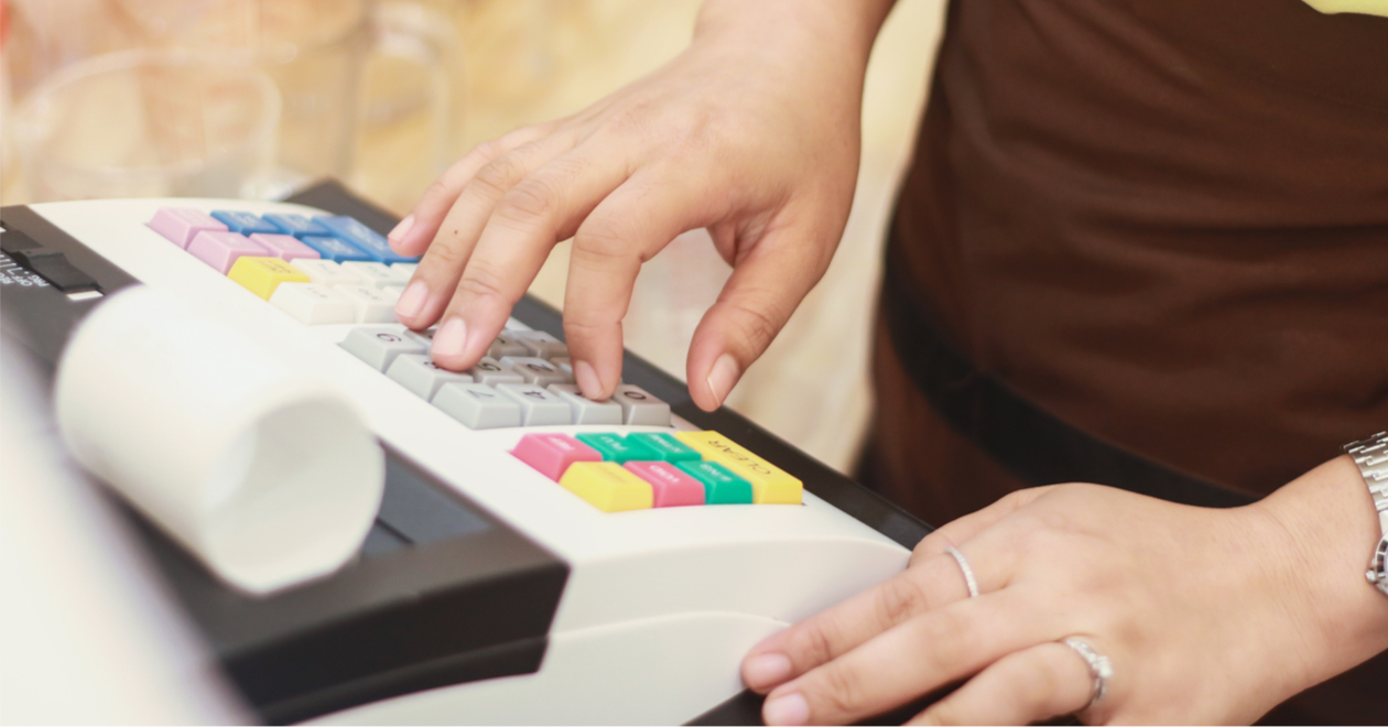 Close-up of hands using a cash register.