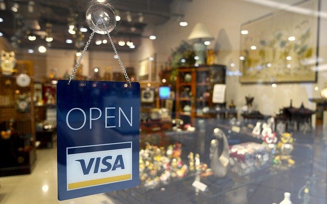 Shop's glass door with sign stating open and uses VISA