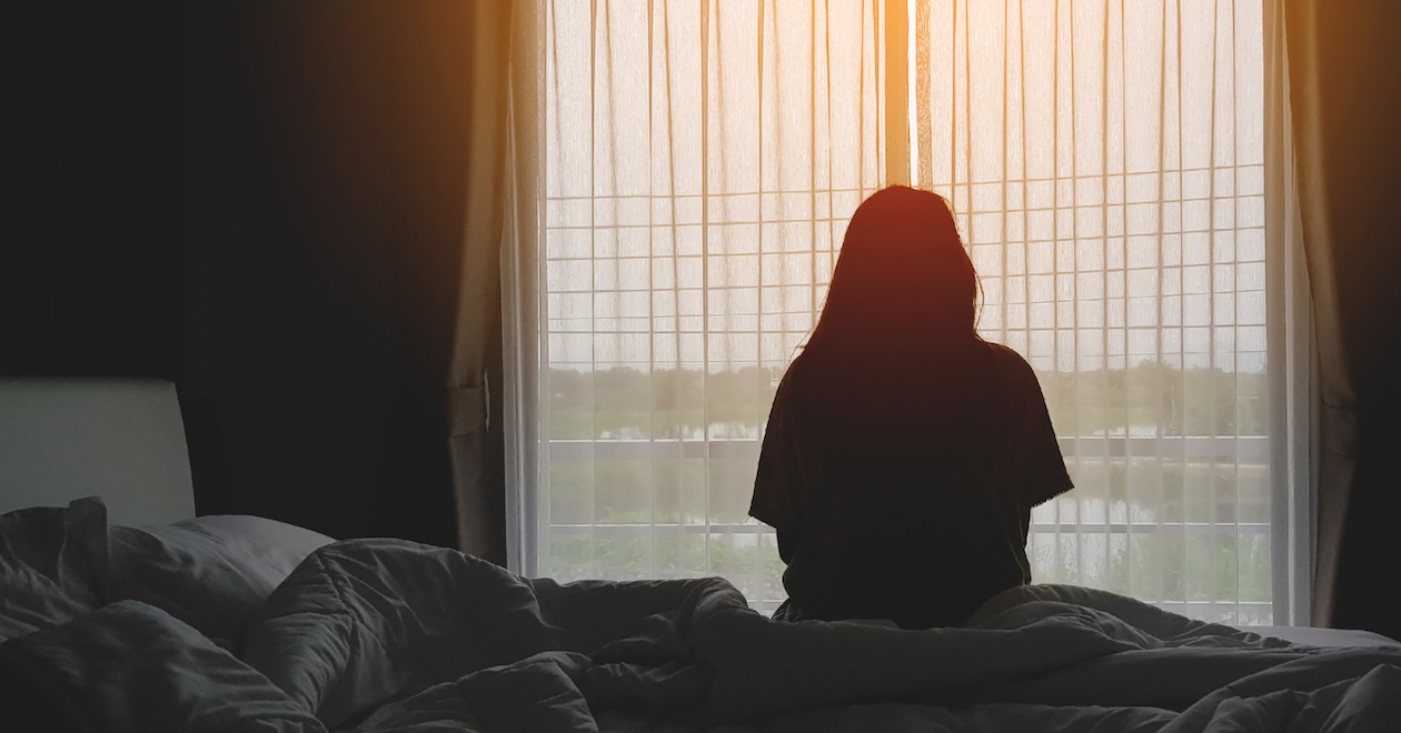 A woman in silhouette in front of a hotel room window