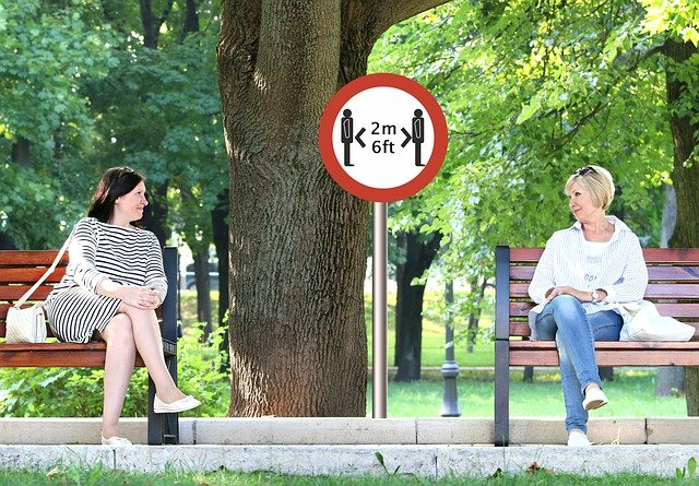 Two people social distancing on benches