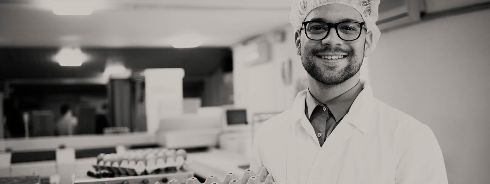 Man in a lab coat holding egg boxes