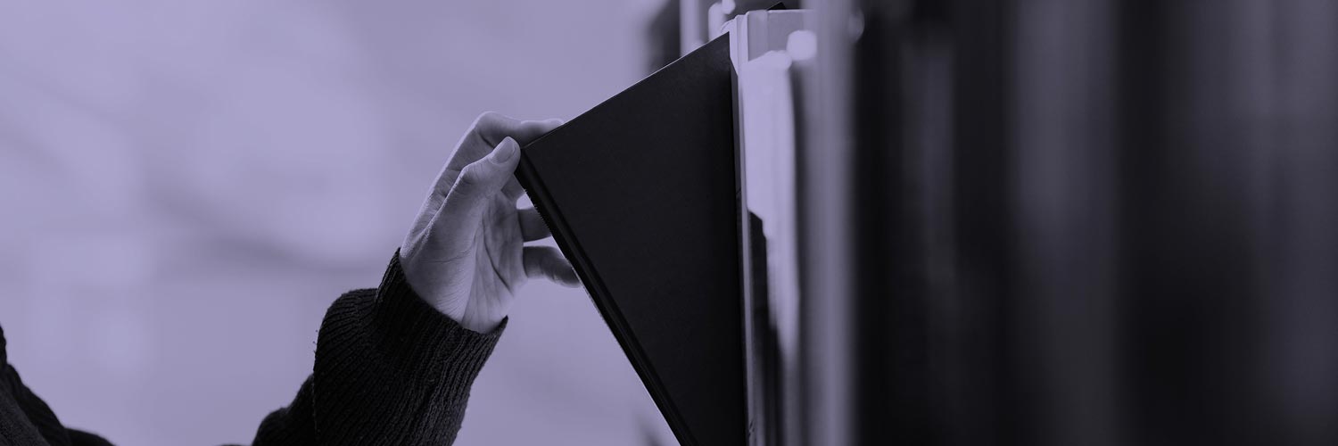 A person lifting a book from a shelf