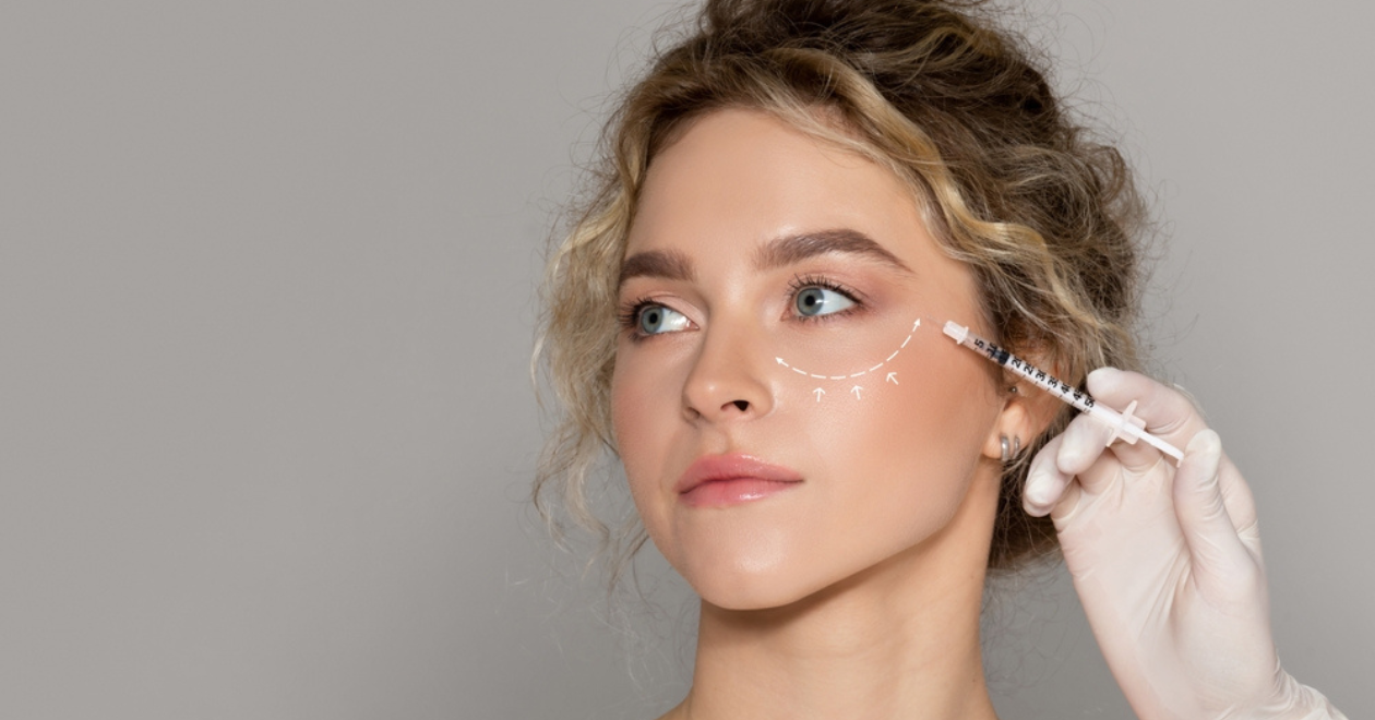 Young woman with drawn line under her eye and needle held next to her face